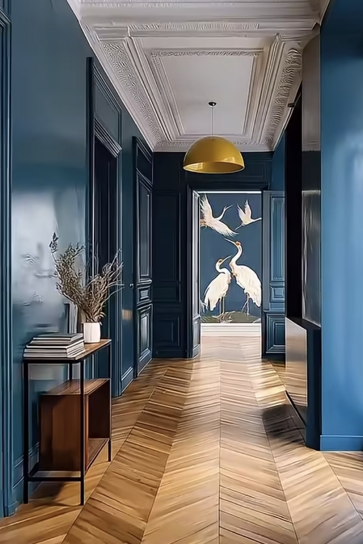 Deep blue paneled hallway with chevron wood floors and crane mural